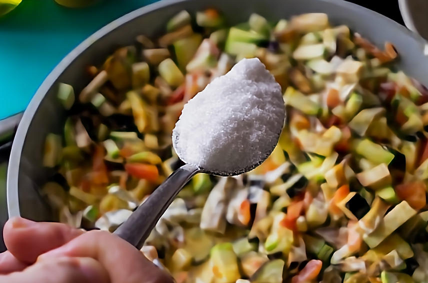Une cuillère remplie de sel au-dessus d'un bol de nourriture